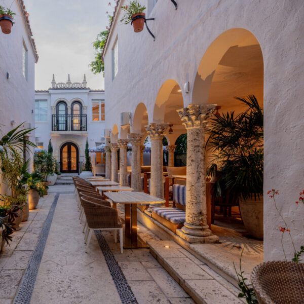 A serene courtyard with white walls, arches, columns, and seating areas.