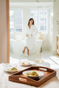 Woman enjoying breakfast in bed in a stone arch suite at Donatella Hotel, the most instagrammable honeymoon suite Miami offers for couples